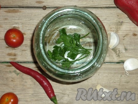 Петрушку промыть под проточной водой. Чеснок очистить. Горький перец нарезать на колечки шириной 0,5 сантиметров. Из болгарского перца удалить семена, нам потребуется 2 колечка перца шириной 0,5 сантиметров.&nbsp; Банки заранее простерилизовать любым удобным способом (я стерилизовала над паром), крышки прокипятить в течение 3-4 минут с момента закипания воды. На дно каждой подготовленной банки выложить по 2 веточке петрушки.