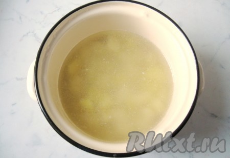 В кастрюлю налить 2 литра воды, выложить кусочки курицы, поставить на огонь, с момента закипания, убрав пену, варить на минимальном огне минут 25. Затем мясо вынуть. Я отваренное мясо не добавляю в рассольник, а использую его для приготовления других блюд. При желании, вы можете, отделив мясо от костей, вернуть его в бульон. Поставить кастрюлю с бульоном на огонь, дать закипеть. Картофель почистить, помыть и нарезать на кубики среднего размера. Добавить нарезанный картофель в кастрюлю с бульоном.