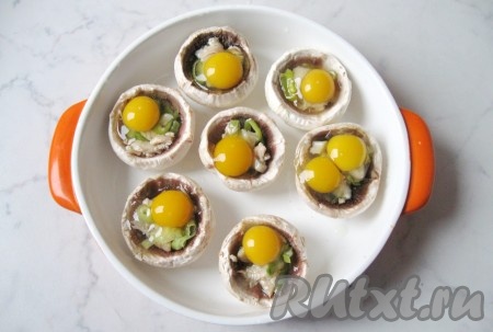 Перепелиные яйца разбить и выложить в каждую шляпку шампиньона на начинку.

