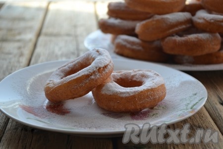 Готовые пончики выкладываем на салфетку, чтобы убрать лишний жир. Затем перекладываем на тарелку, даём немного остыть и посыпаем сахарной пудрой. Постепенно жарим во фритюре все творожные пончики.