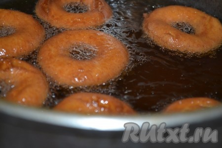 На столе, присыпанном мукой, раскатываем тесто до толщины приблизительно 1 сантиметр и вырезаем с помощью чашки кружочки или бублики. Я сделала пончики и в форме кружочков, и в форме бубликов. Для того чтобы получить пончик в форме бублика, с помощью чашки вырезаем из теста кружочки, в середине каждого круга вырезаем отверстие меньшего размера (я отверстие внутри кружка вырезаю с помощью пробки от пластиковой бутылки). В глубокой сковороде (или в кастрюле с толстым дном) разогреваем достаточно большое количество подсолнечного масла (фритюр), огонь уменьшаем до среднего. Затем выкладываем несколько заготовок творожных пончиков и жарим их с двух сторон до золотистости.