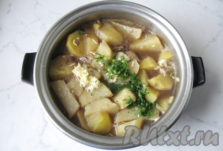 После закипания готовить жаркое из свинины с сушёными грибами минут 25-30 (до мягкости картофеля), затем добавить мелко нарезанные чеснок и укроп.