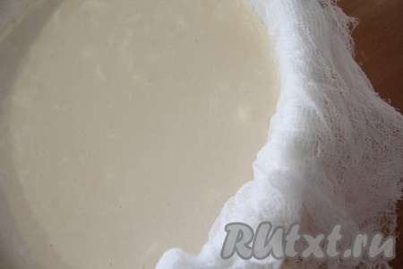 Дуршлаг поставить поверх глубокой кастрюльки. В дуршлаг, застеленный тремя слоями марли, аккуратно вылить получившуюся смесь из ряженки, сметаны и соли. В кастрюлю, на которой стоит дуршлаг, будет стекать лишняя жидкость, выделяющаяся из кисломолочной смеси. Можно получившуюся конструкцию в таком виде поставить в холодильник, а я оставила дуршлаг на столе на час, за это в кастрюлю стекла большая часть жидкости.