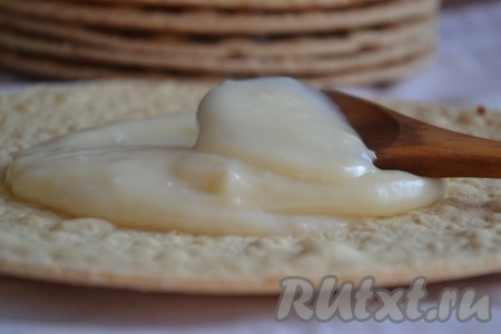 Затем снимаем с огня и даём заварному крему полностью остыть. Когда заварной крем остынет, начинаем собирать медовик. Для этого на плоскую тарелку вкладываем первый корж, смазываем его частью заварного крема, сверху кладём следующий корж, тоже смазываем его кремом, продолжая чередовать коржи и крем, собираем весь торт. Верхний корж тоже смазываем кремом.