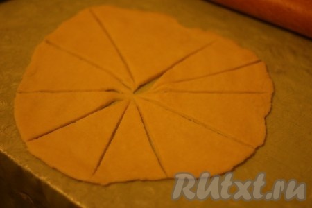 Тесто раскатать в круг толщиной около 0,5 см, разделить его на треугольники. 