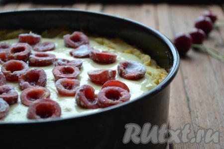 Дно разъёмной формы для выпечки смазываем растительным маслом. Песочное тесто распределяем по дну форму, формируя бортик. Тесто на дне формы накалываем вилкой, чтобы оно не поднималось во время выпечки. Выкладываем на песочную основу пирога творожную начинку. Сверху кладём ягоды вишни и немного утапливаем их в начинку.