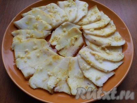 Далее с каждого кусочка сала ножом соскоблить немного соли и специй, разложить сало на тарелке и посыпать измельчённым (или пропущенным через пресс) чесноком.