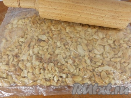 Затем арахис измельчить. Слишком мелко не измельчать, поэтому лучше всего поместить его в пакет и скалкой прокатать несколько раз.