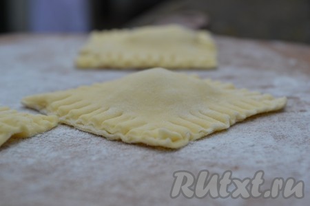 Сверху накрыть второй частью теста. Разрезать на квадратики с начинкой по середине (будущие равиоли) и защепить края теста при помощи вилки.
