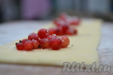 Тесто раскатать в тонкий пласт квадратной формы и разрезать на две равные части. Выложить на одну из них подготовленную смородину и посыпать сахаром. Выкладывать необходимо на одинаковом расстоянии кучками, примерно, по столовой ложке ягод.
