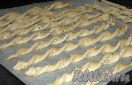 Полоску из теста несколько раз перекрутить. Получится палочка, которая будет напоминать спираль, как на фото. Переложить палочку с кунжутом на противень, застеленный пергаментом. Аналогично сформировать и выложить на застеленный противень все палочки с кунжутом.