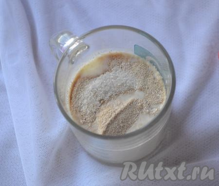 Первым делом сделаем опару для теста, для этого в чашку нужно налить 150 миллилитров молока, предварительно подогретого до 38-40 градусов, всыпать сухие дрожжи, половину столовой ложки сахара, перемешать. Оставить опару минут на 15 в тёплом месте. За это время дрожжи заработают и опара покроется пышной шапочкой.