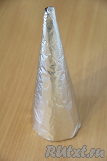 Приготовить каркас для нашей ёлочки. Из плотной бумаги сделать конус, а затем обвернуть его пищевой фольгой. Высоту и ширину ёлочки определяйте сами.&nbsp;
