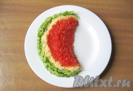 Помидор разрежьте и удалите мякоть и семена. Должна остаться только плотная часть помидора. Мелко нарежьте эту часть и выложите мякоть арбузной дольки.
