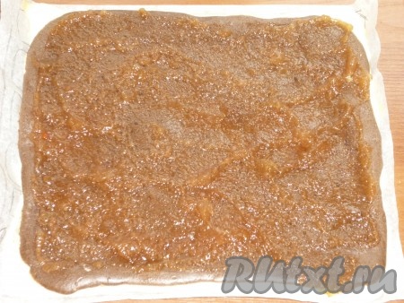 Готовый корж достаём из духовки и смазываем любимым повидлом. Сворачиваем его с помощью бумаги, на которой он выпекался.