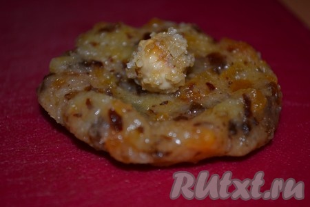 Из смеси сухофруктов и риса скатать небольшие шарики. Каждый шарик приплюснуть, чтобы получилась лепешка, в центр которой положить орешек.
