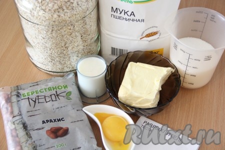 Подготовить продукты для приготовления овсяного печенья с арахисом. Сливочное масло для замешивания теста должно быть мягким, поэтому заранее достаньте его из холодильника, постепенно оно согреется до комнатной температуры и размягчится.