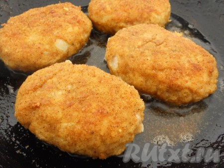 На сковороде разогреть растительное масло, выложить котлеты, сформированные из куриного фарша с сыром, жарить их с одной стороны на среднем огне 4-5 минут (до подрумянивания снизу), затем перевернуть и жарить ещё 4-5 минут. Снова перевернуть котлетки, влить в сковороду совсем немного воды, дать воде закипеть. Накрыть сковороду крышкой и протушить котлетки в течение 7-8 минут. Затем открыть крышку, посыпать котлеты оставшимся сыром. Сыр сразу начнёт плавиться на горячих котлетках.