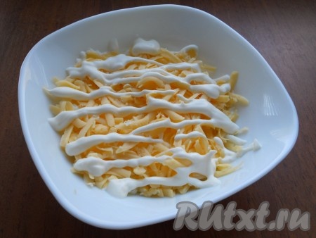 Следующим слоем выложить сыр, натёртый на крупной тёрке, нанести немного майонеза.