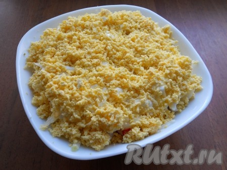 Последний слой салата - натёртые на мелкой тёрке варёные желтки. Желтками нужно покрыть и верх, и бока салата. Немного присолить желтки. Майонезом не смазывать.