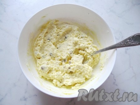 Начать вмешивать муку в творожное тесто. Затем добавлять муку по столовой ложке, каждый раз вмешивая её в тесто. Творожное тесто должно получиться липким, комковатым и держащимся на ложке. Из него можно руками слепить сырник и он будет держать форму. Как только добились такой консистенции, больше муку не добавляйте.