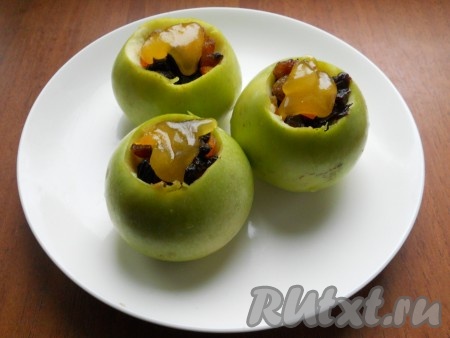 Сверху изюма на каждое яблоко выложить по 1 чайной ложечке мёда. Переставить яблоки, фаршированные изюмом и мёдом, в форму для запекания и отправить в духовку, разогретую до 180 градусов, на 20-40 минут. Готовность можно проверить, проколов печёное яблоко зубочисткой (если зубочистка легко входит в мякоть яблока, значит оно готово). Запечённые яблоки должны стать мягкими, но при этом они должны держать форму (то есть не должны разваливаться). Продолжительность запекания зависит от размера яблок и сорта, поэтому лучше следить за процессом запекания.