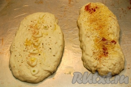 Из оставшегося теста формируем две продолговатые лепёшки, одну посыпаем нарезанными дольками свежего чеснока, а другую - оставшимся сыром. Сверху лепёшки, по желанию, посыпаем орегано (можно добавить и другие специи по вкусу), сбрызгиваем оливковым маслом.