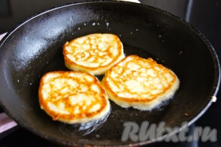 Жарить сырные оладьи на среднем огне до румяности с двух сторон (примерно по 2-3 минуты с каждой стороны). Готовые оладьи переложить на тарелку, застеленную бумажным полотенцем, чтобы удалить лишнее масло. Периодически перемешивая тесто, постепенно пожарить все оладушки, складывая их горкой на тарелку.