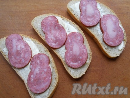 На хлеб с маслом поместить по 2-3 тонких кружочка колбасы.