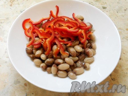 Консервированную красную фасоль без жидкости выложить в сито, промыть под проточной водой, дать стечь лишней воде. Поместить подготовленную консервированную (или отваренную) фасоль в глубокую миску.&nbsp;Из болгарского перца удалить семена (с цветным перцем салат будет выглядеть ярче, поэтому я взяла красный перец), затем нарезать его тонкой соломкой и выложить в миску с фасолью.
