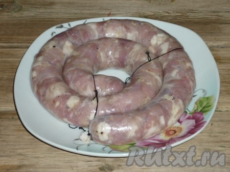 Надеть на мясорубку специальную насадку (сетку и нож нужно из мясорубки убрать). На трубку нанизать кишку (конец кишки завязать), а затем не очень плотно наполнить оболочку мясом.&nbsp;Колбасу свернуть колечком и перевязать ниткой, в нескольких местах проколоть оболочку иглой.

