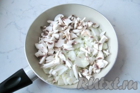 Шампиньоны и репчатый лук почистить, помыть и мелко нарезать. Выложить на сковороду и налить подсолнечное масло.
