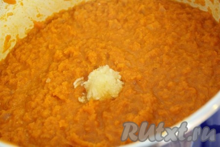 Чеснок почистить и пропустить через пресс. Кастрюлю с морковной икрой поставить на огонь, добавить измельчённый чеснок и влить уксус. Всё тщательно перемешать, довести овощную смесь до кипения и снять с огня.