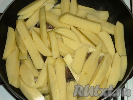 Очистить картошку, лук и чеснок. Картофель нарезать на достаточно крупные брусочки и отправить к обжаренному мясу.