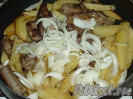 Когда картофель будет почти готов, добавить в сковороду лук, нарезанный полукольцами, и пропущенный через пресс, перемешать, накрыть сковороду крышкой и готовить ещё 10 минут. За это время 1-2 раза перемешать картофель со свиными рёбрами.