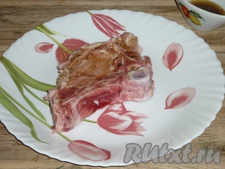 Свиную корейку на кости промыть под проточной водой, разрубить по ребру и обсушить бумажным полотенцем. Обмазать каждый кусочек мяса со всех сторон смесью масла, соли и специй. Оставить мясо на 30 минут, чтобы оно просолилось, хорошо пропиталось специями и растительным маслом.