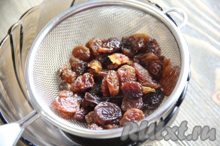 Изюм обдать кипятком, а затем откинуть на дуршлаг и дать стечь воде.