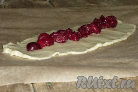 По истечении времени каждую часть теста раскатать в прямоугольник, выложить вишню, аккуратно защипнуть края.
