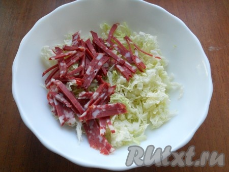 Капусту пекинскую тоненько нарезать, слегка присолить и немного помять рукой. Добавить к капусте копченую колбасу, нарезанную тоненькой соломкой.
