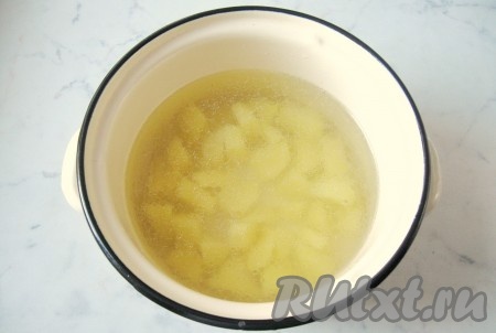 Готовый бульон процедить и налить в кастрюлю 1,5 литра. Картофель почистить, помыть и нарезать кубиками. Выложить картофель в кастрюлю с бульоном. Накрыть кастрюлю крышкой и поставить на плиту. Начать варить рассольник.
