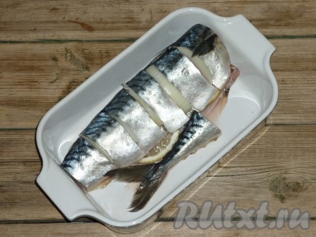 В форму для запекания (при желании форму можно смазать растительным маслом) выложить скумбрию, посолить её внутри и снаружи. Между кусками рыбы вставить кольца лука. Внутрь брюха выложить ломтики лимона.