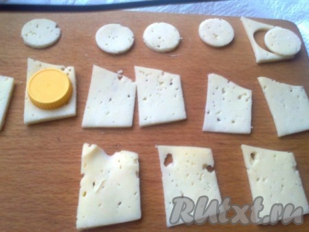 Для приготовления сырных роз надо сначала нарезать часть твердого сыра тонкими пластинками, затем вырезать из пластинок крышкой из-под минералки кружочки. На каждую розу понадобится 9 кружочков
