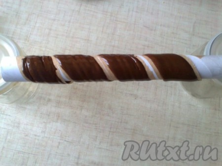 Закрепляем края полоски в свернутом в спираль виде с помощью скотча на рулоне от пергаментной бумаги. Даем застыть шоколаду. У меня застывал между двумя 0,5-литровыми банками. Охладить.
