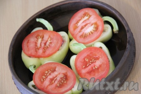 На дно жаропрочной формы налить немного воды. Выложить перцы с фаршем. Помидор вымыть и нарезать кружочками. На каждый перчик, поверх фарша, выложить кусочек помидора.