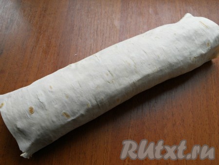 Затем сверху поместить второй лист лаваша, придавить его рукой. Далее все повторить: сеточка майонеза, курица с петрушкой и морковь. Свернуть лаваш с начинкой в плотный рулет, сухие концы отрезать.
