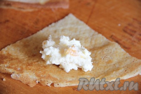 На каждую часть выложить по 1/2 чайной ложки творожной массы и закрутить каждую часть в трубочку. Таким образом сформировать все налистники с творогом.
