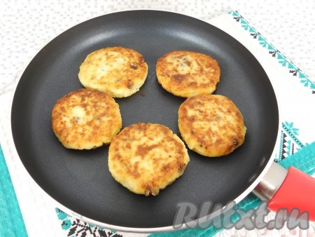 Выкладывать заготовки сырников на разогретую с растительным маслом сковороду, жарить на среднем огне до румяности с двух сторон (примерно по 3-4 минуты с каждой стороны). Затем переложить на тарелку, постепенно пожарить все сырники.