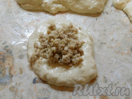 Стол смазать растительным маслом и выложить тесто. Руками, также смазанными маслом, разделить тесто на части, каждую часть растянуть в лепешку (лепешки должны быть не тонкими). В середину лепешки поместить 1 столовую ложку мясного фарша.
