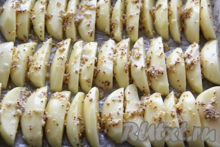 Противень для запекания застелить пергаментом и слегка смазать растительным маслом. Выложить картофель на противень в один слой. Поставить противень в разогретую духовку и запекать при 200 градусах сначала с нижним нагревом 25 минут, а затем 25 минут с верхним нагревом. Таким образом нам не нужно переворачивать картошку, она равномерно запечётся и покроется румяной корочкой. Готовность проверить зубочисткой или вилкой.
