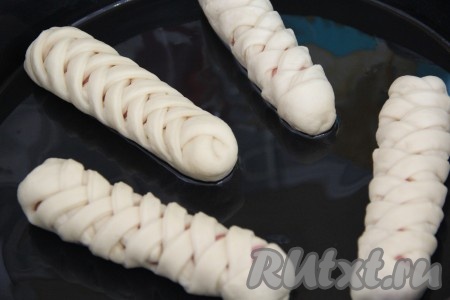 Сосиски в тесте, завёрнутые в дрожжевое тесто, выложить на противень, смазанный растительным маслом и оставить на 15-20 минут в тёплом месте для подъёма.